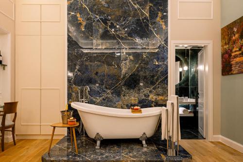 a bathtub in a bathroom with a marble wall at Curcumelli Luxury Suites in Corfu Town
