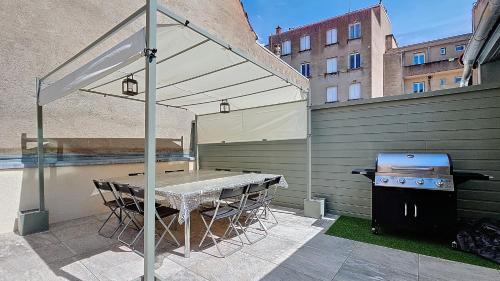 un patio avec un grill et une table avec un auvent dans l'établissement Résidence du Théâtre, appartements avec ou sans SPA, à Moulins