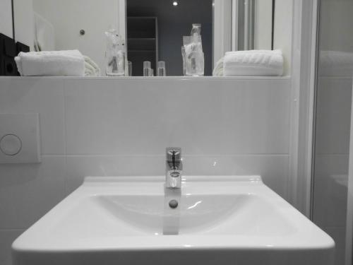 a white sink in a bathroom with a mirror at Novitel Hotel Kirchheim - München Messe in Kirchheim