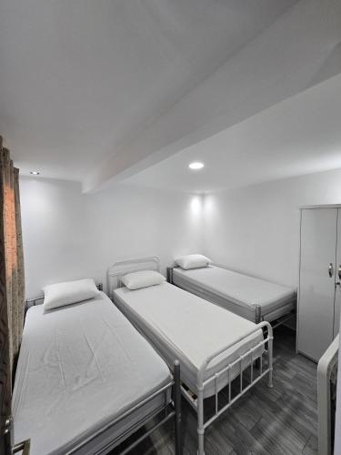 three beds in a room with white walls at Taghazout Flats in Taghazout