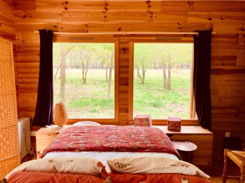 une chambre avec un lit et une grande fenêtre dans l'établissement Eco-Friendly Boho Loft Chalet, à Saint-Julien-en-Born