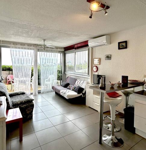 une cuisine et un salon avec un canapé et une table dans l'établissement Agréable studio accès à la plage - parking - 2BALM2, au Barcarès