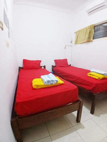 two beds in a room with red and yellow sheets at Moshi Moshi in Probolinggo