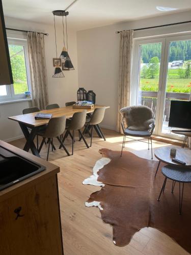 a living room with a wooden floor with a table and chairs at Haus Alpentraum in Patergassen