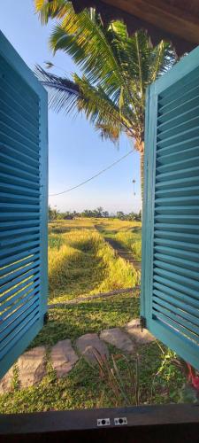 a view of a palm tree from a open door at D'Ume Bendoel Homestay in Jatiluwih