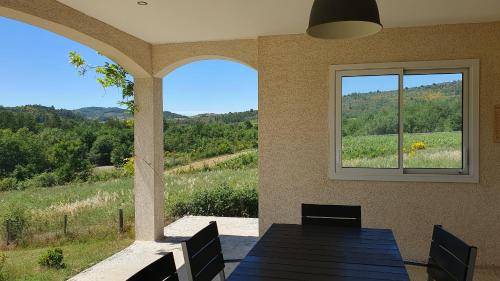 a porch with a table and a window with a view at Le Gîte de Berignac in Antugnac