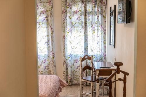 Pokój ze stołem i oknem z zasłonami w obiekcie Hotel Las Rosas w mieście Priego de Córdoba