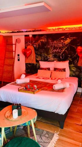 a bedroom with a large bed and a table at Jungle Love avec Balnéo à 10 min de Disneyland Paris in Serris