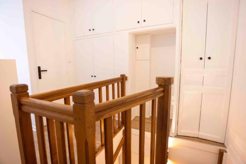 une pièce avec un escalier en bois et des armoires blanches dans l'établissement DUPLEX AU COEUR DU 16 Eme, à Paris
