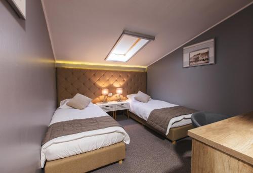 a room with two beds and a desk with lights at Hotel - Pansion Kod Ruže - Strossmayer No 1 - breakfast included in Osijek