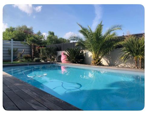 une grande piscine bleue avec des palmiers en arrière-plan dans l'établissement Family villa, à Plaisance-du-Touch