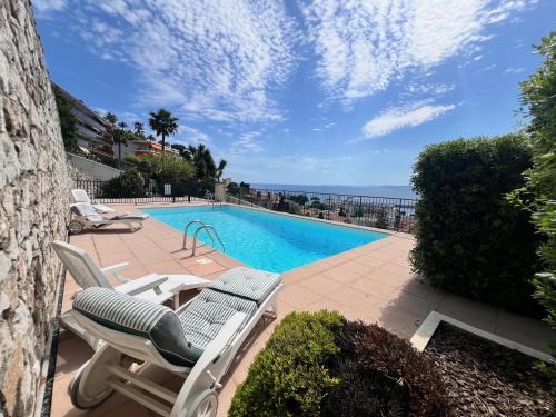 - une piscine avec 2 chaises longues et l'océan dans l'établissement ApartHotel Riviera - TERRASSE DES AGAVES - Amazing Sea View Nice Côte d'Azur, à Nice