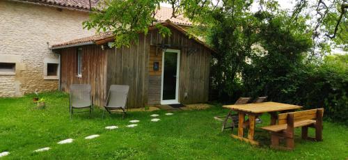 a picnic table and chairs in a yard next to a cabin at La Maison des Escargots in Blanzay