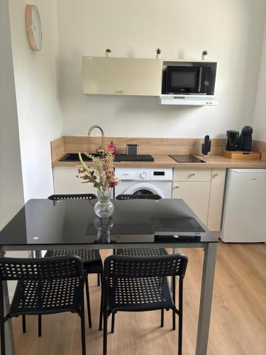 une cuisine avec une table noire, des chaises et un four micro-ondes dans l'établissement Un Havre de Paix à Poitiers, à Poitiers
