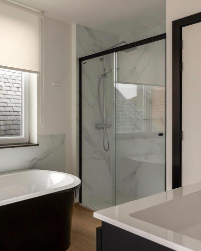 a bathroom with a tub and a glass shower at Comic Art Hotel in Ghent