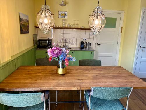 a dining room table with a vase of flowers on it at B & B De Rozengracht in Doesburg