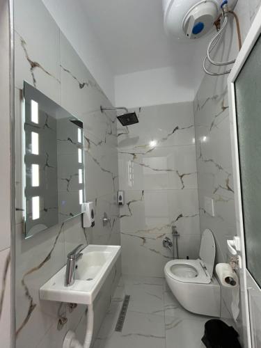 a white bathroom with a toilet and a sink at Vila Roan in Vlorë