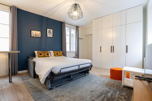 une chambre avec un lit et un mur bleu dans l'établissement Smart Inn Fontainebleau Centre- Studio, à Fontainebleau