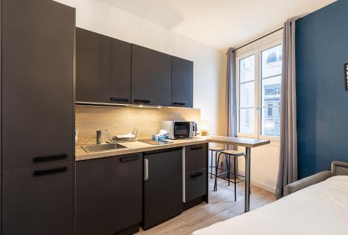 une cuisine avec un évier et un plan de travail dans l'établissement Smart Inn Fontainebleau Centre- Studio, à Fontainebleau