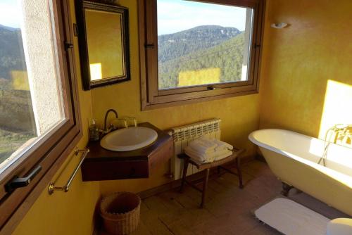 baño con bañera, lavabo y ventana en El Folló Turisme Rural en Tagamanent
