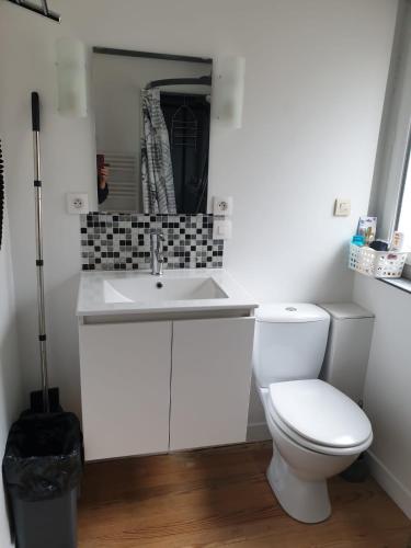 une salle de bain avec des toilettes blanches et un lavabo dans l'établissement La maison de Nadège, à Lion-sur-Mer