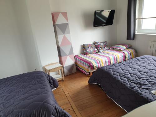 Un dormitorio con una cama, un sofá y un televisor. en La maison de Nadège, en Lion-sur-Mer