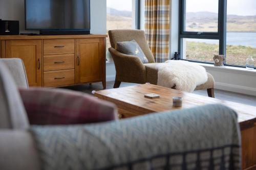 a living room with chairs and a tv and a table at Modern and Dog Friendly Holiday Home with Sea Loch Views in Breaclete