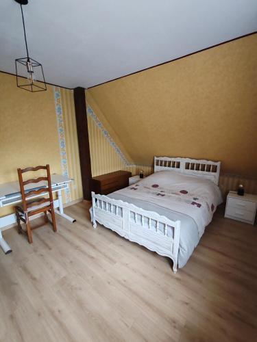 - une chambre avec un lit blanc et un fauteuil en bois dans l'établissement Beaux prés 68, à Colmar