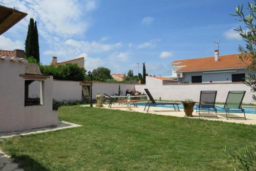 une cour avec deux chaises et une table ainsi qu'une maison dans l'établissement Villa familiale piscine privée 6 personnes Proche plage 6PC7, à Saint-Laurent-de-la-Salanque