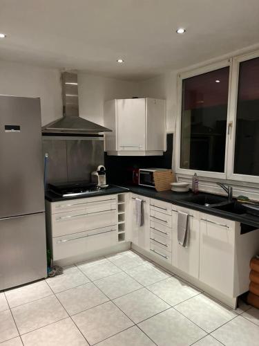 une cuisine avec des armoires blanches et des appareils électroménagers blancs dans l'établissement avem-dam, à Dammartin-en-Goële