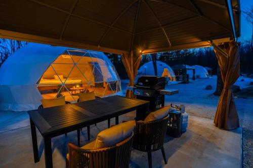 a table and chairs under a tent with a grill at Private Glamping NAGOMI CAMP in Nasushiobara