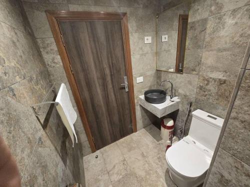 a bathroom with a toilet and a sink and a door at La Luna in Bangui