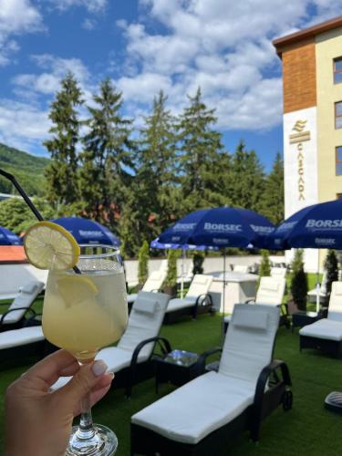 a person holding a drink with a slice of lemon at Hotel Cascada BAILE OLANESTI in Băile Olăneşti