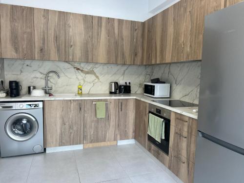 cocina con armarios de madera, lavadora y secadora en Maroulla's Urban Beach Living, en Limassol