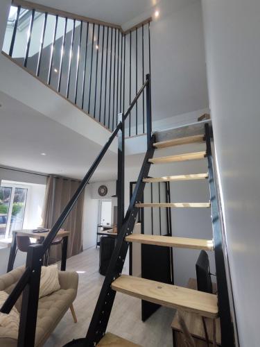 un escalier dans un salon avec un canapé et une table dans l'établissement Studio neuf situé au cœur d'un bourg paisible, à Pacé