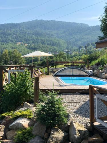 a swimming pool in a yard with a umbrella at Gościniec Rajec in Rajcza
