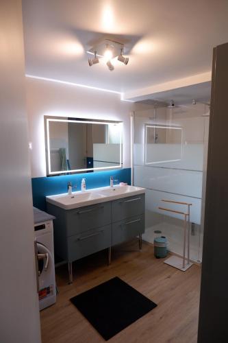 une salle de bain avec un lavabo et un miroir dans l'établissement maison familiale proche plage, à Quiberville