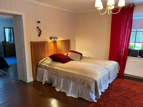 a bedroom with a bed with two red pillows on it at Stort lantligt hus för upp till 12 gäster in Rönneshytta