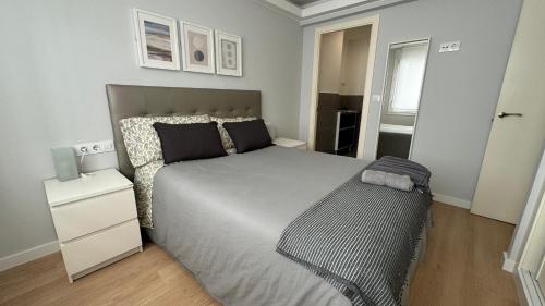 a bedroom with a large bed and a night stand at Apartamento Cancela, super luminoso y bien situado in A Coruña