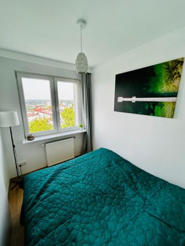 a bedroom with a green bed and two windows at Cliff Apartment Redłowo in Gdynia