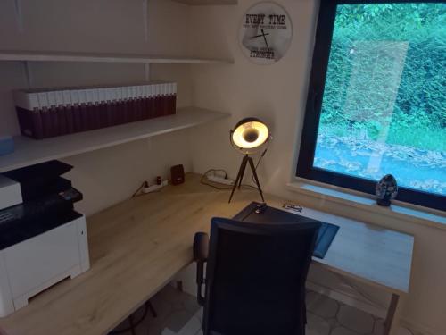 a desk with a lamp in a room with a window at Boshuisje in Couvin