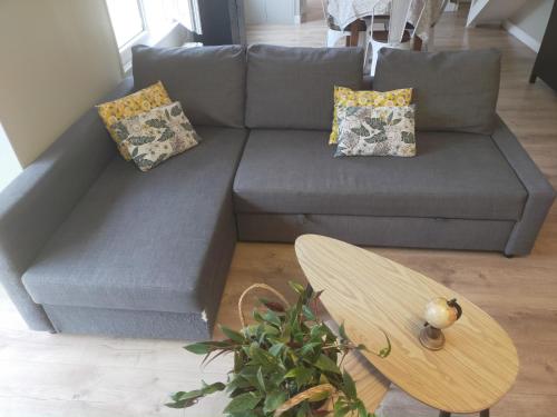 a grey couch with pillows and a wooden table at Loc MI in Carentan