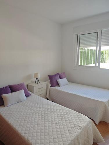 two beds in a white room with purple pillows at Apartamento A & M in Vera