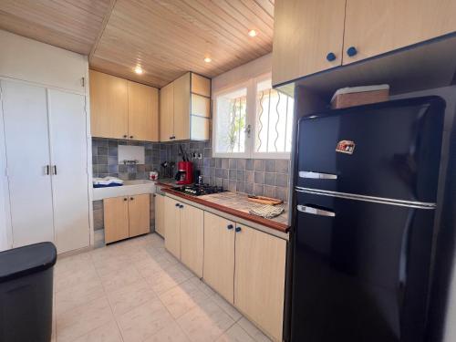 une cuisine avec un réfrigérateur noir et des armoires en bois dans l'établissement Maison au calme vue mer à 180, à Toulon