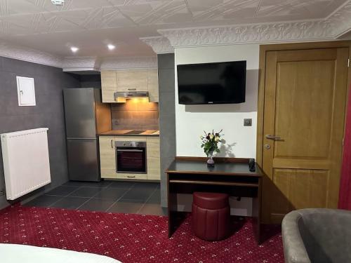 a room with a kitchen with a table and a television at Hotel Eikenhof in Aalter
