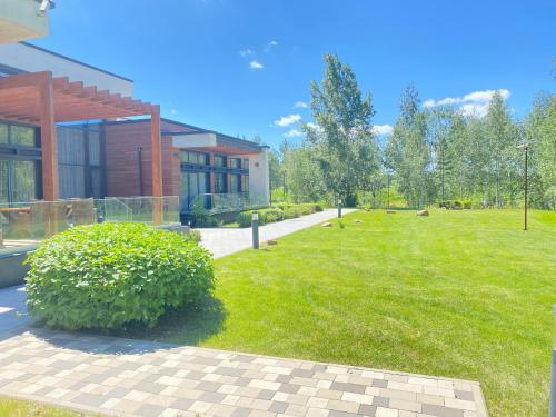 a house with a green yard next to a building at Hotel Burabay in Shchūchīnsk