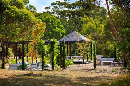 デイルスフォードにあるBodhi Daylesford - family friendly group accommodation with poolの公園内のガゼボ(ソファ、椅子付)