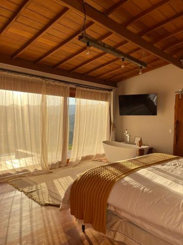a bedroom with a bed and a tub and a television at Cabana Girassol com piscina aquecida e cesta para café da manhã in Gonçalves