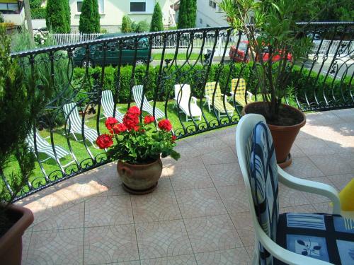 a balcony with chairs and a vase of flowers at Erika Apartmanházak in Hévíz