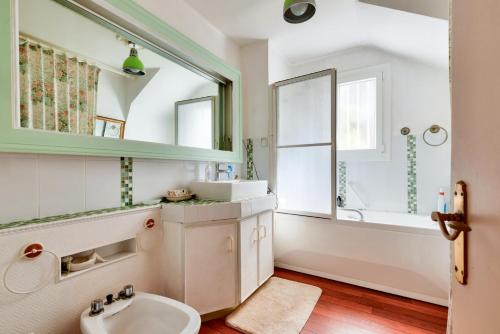 une salle de bain avec un lavabo, une baignoire et un miroir dans l'établissement Maison 3 chambres 200m de la mer, à La Pironnière
